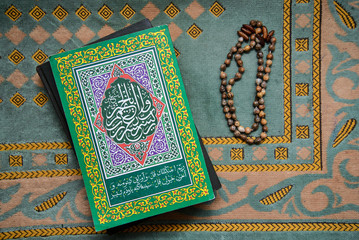 The Koran and the old rosary on a green mat