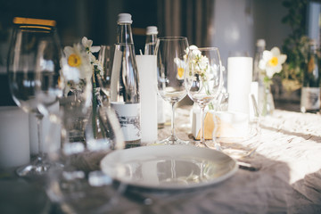 Table setting for dinner in restaurant on the sunset, served wedding table with decor as candles, flower arrangements, wine glasses, water