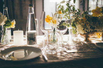 Table setting for dinner or banquet in restaurant on the sunset. Wedding festive interior, table decorations, flowers, table setting, wine glass, pastel summer tones