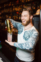 Bearded barman prepares a cocktail and smiles