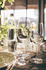 Wedding banquet at sunset. Table for guests, decorated with candles and flowers, served with wineglasses and water and covered with a tablecloth. Table decorated for the wedding reception. Vertical