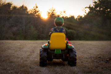 Toddler riding tractor into sunset