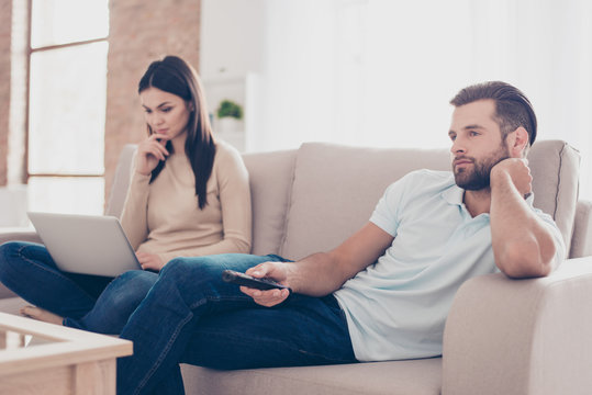 Photo of two people in love spending their spare time separately by using laptop and watching tv