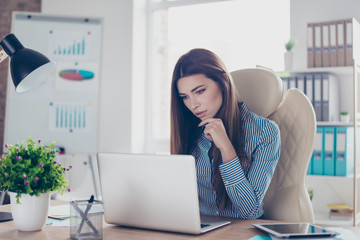 Portrait of serious young businesswoman in formal wear, sitting at her work place and concentrated...