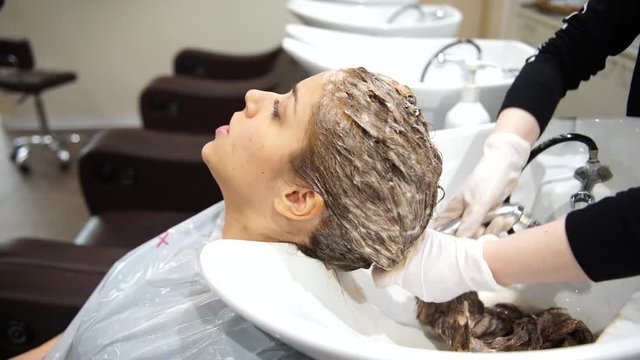 A young beautiful woman getting her hair washed at hairdressers, 4K