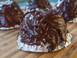 Making  homemade chocolate bowl by pouring a liquid chocolate on a foil-covered cupi
