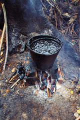 A bucket of black tar boils on the fire for use in repair and waterproofing.