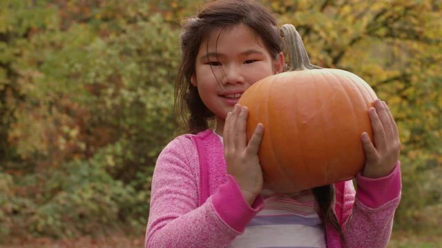 Young girl in Fall holding pumpkin