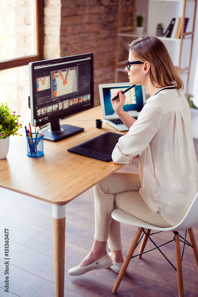 Fototapete vertical photo of attractive young photographer working with computer at the table and retouching wi