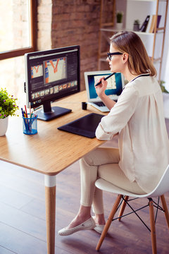 Vertical photo of attractive young photographer working with computer at the table and retouching with computer