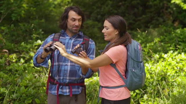 Couple hiking takes break to look through binoculars