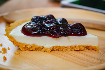 Blueberry cheesecake on wood plate.