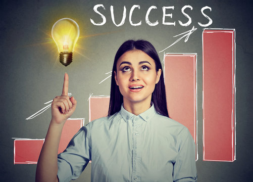 Successful woman looking up at idea light bulb with growing success chart