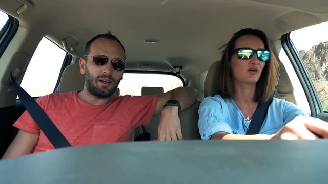 Young couple in car talking, woman driving
