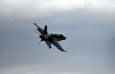 Silhouette of F18 Hornet fighter aircraft in flight. Clouds in the background.