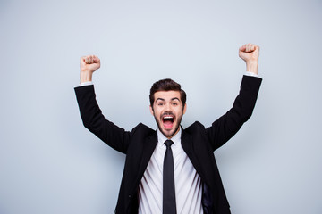 Happy excited man triumphing with raised fists on gray background