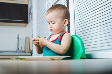 Mixed race girl shelling pea pod at dining table