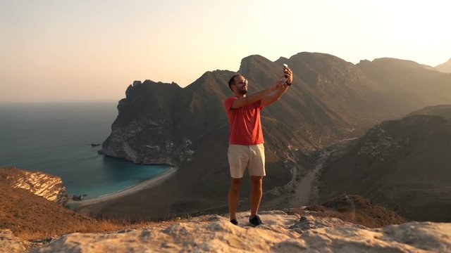 Happy man taking selfie photo with cellphone with amazing bay view in mountains
