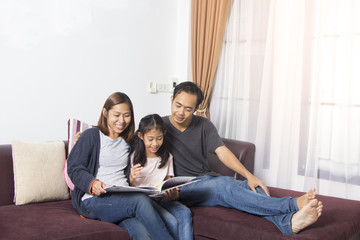 Parents sitting with daughter reading story indoors