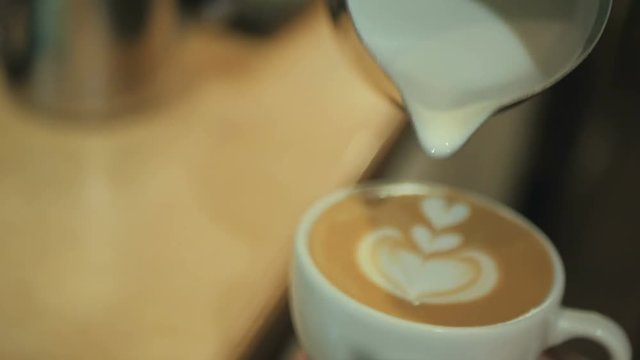 The man drawing the milk over the coffee