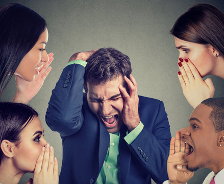 Group of people whispering to a desperate stressed business man