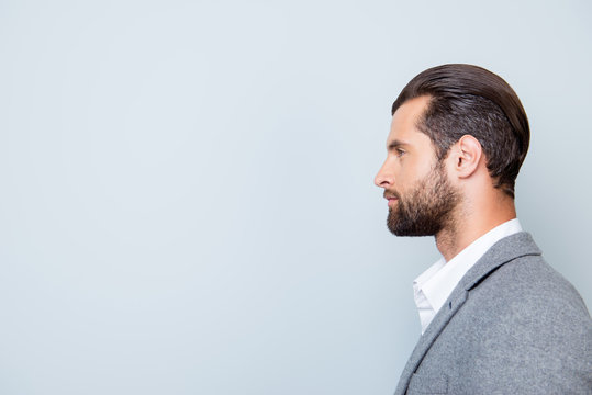 Side view portrait of young serious confident man in suit isolated on gray background