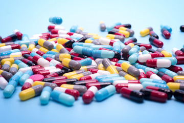 many scattered Colorful pills on blue background.