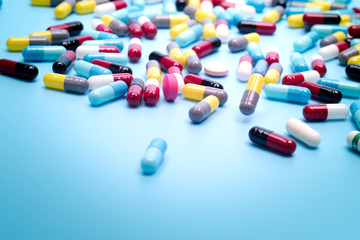 many scattered Colorful pills on blue background.