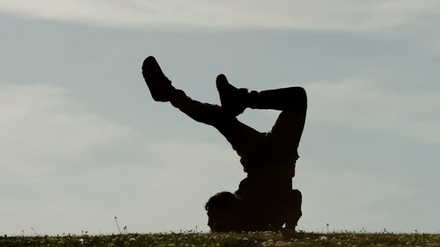 Flexible silhouette male contortionist training outdoors, with space for text