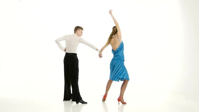 Couple of graceful dancers perform tango on white studio background