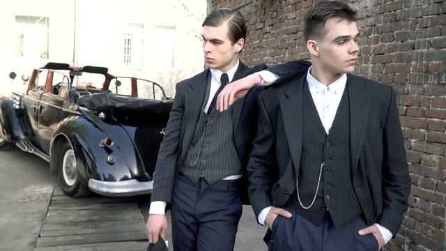Two men in suits near a retro car