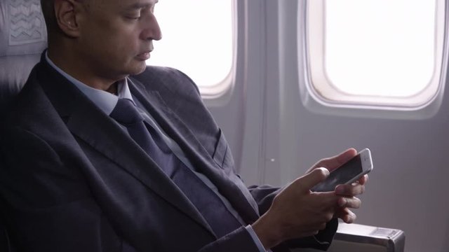 Businessman talking on cell phone on airplane flight