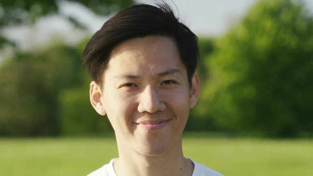 Portrait of smiling asian man looking to camera, in slow motion 