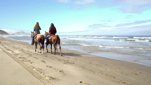 Women riding horses at beach