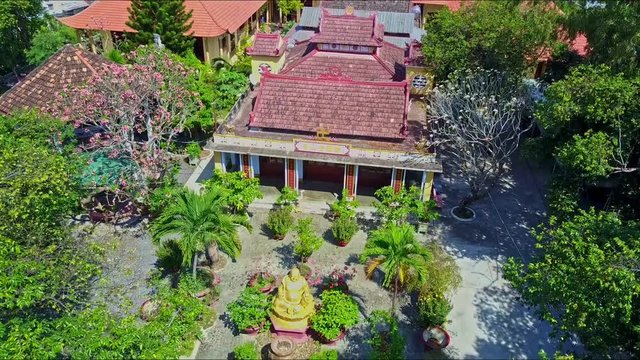 drone flies over green garden with small Buddha statue near nice houses against spectacular mountain and blue sky