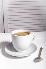 Black coffee in a white cup on a white background. Selective focus. Place for text or inscription. Copy plase. Side view.