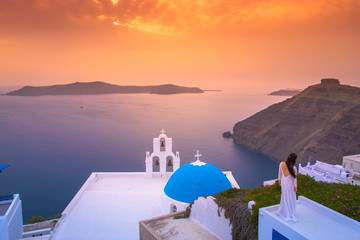 Brilliant sunset at Fira with a church and a bride on a roof, Santorini, Greece. - obrazy, fototapety, plakaty