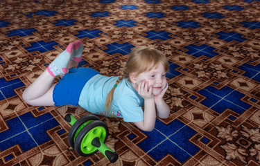 Naklejka premium little girl child is 5 years of playing sports at home itself. He is engaged with the roller, smiling, close-up. Merry training. Healthy lifestyle since childhood.