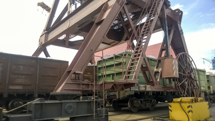 Fototapeta premium Loaded freight cars in the port. Passage of cars under the tower