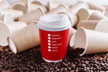 Red paper coffee cup with coffee beans and brown paper cups background
