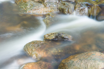 .Waterfall flowing stream is beautiful foam. Traverse the rocks and roots in the woods, good air and cool.