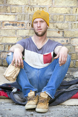 Sad homeless man with alcohol bottle . Social problem