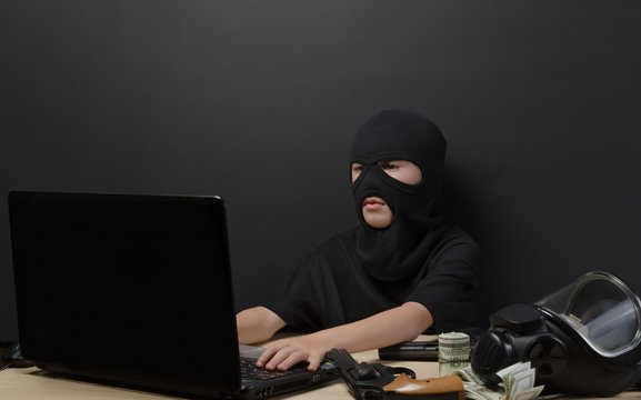 THE LITTLE BOY IN THE MASK OF THE TERRORIST BEHIND A LAPTOP