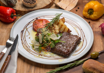 Toliet steak on a white plate surrounded by vegetables on the table in the restaurant