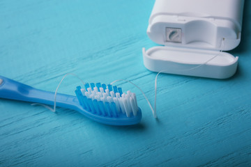 Toothbrush and dental floss on wooden background