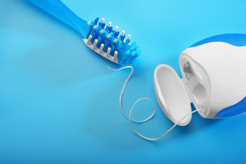 Toothbrush and dental floss on color background