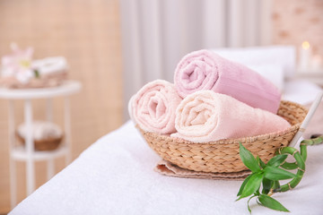 Fototapeta na wymiar Rolled up white spa towels in straw basket