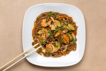 buckwheat noodles with seafood on white plate in restaurant