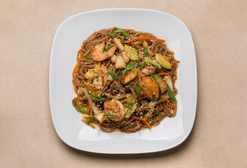 buckwheat noodles with seafood on white plate in restaurant