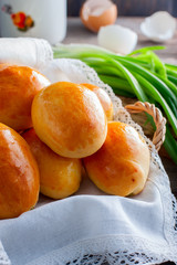 Oven fresh home made baked patties stuffed with eggs and green onion on rustic wooden background. Home cuisine. Close up delicious stuffed home cooking pastries on an orange plate and napkin.